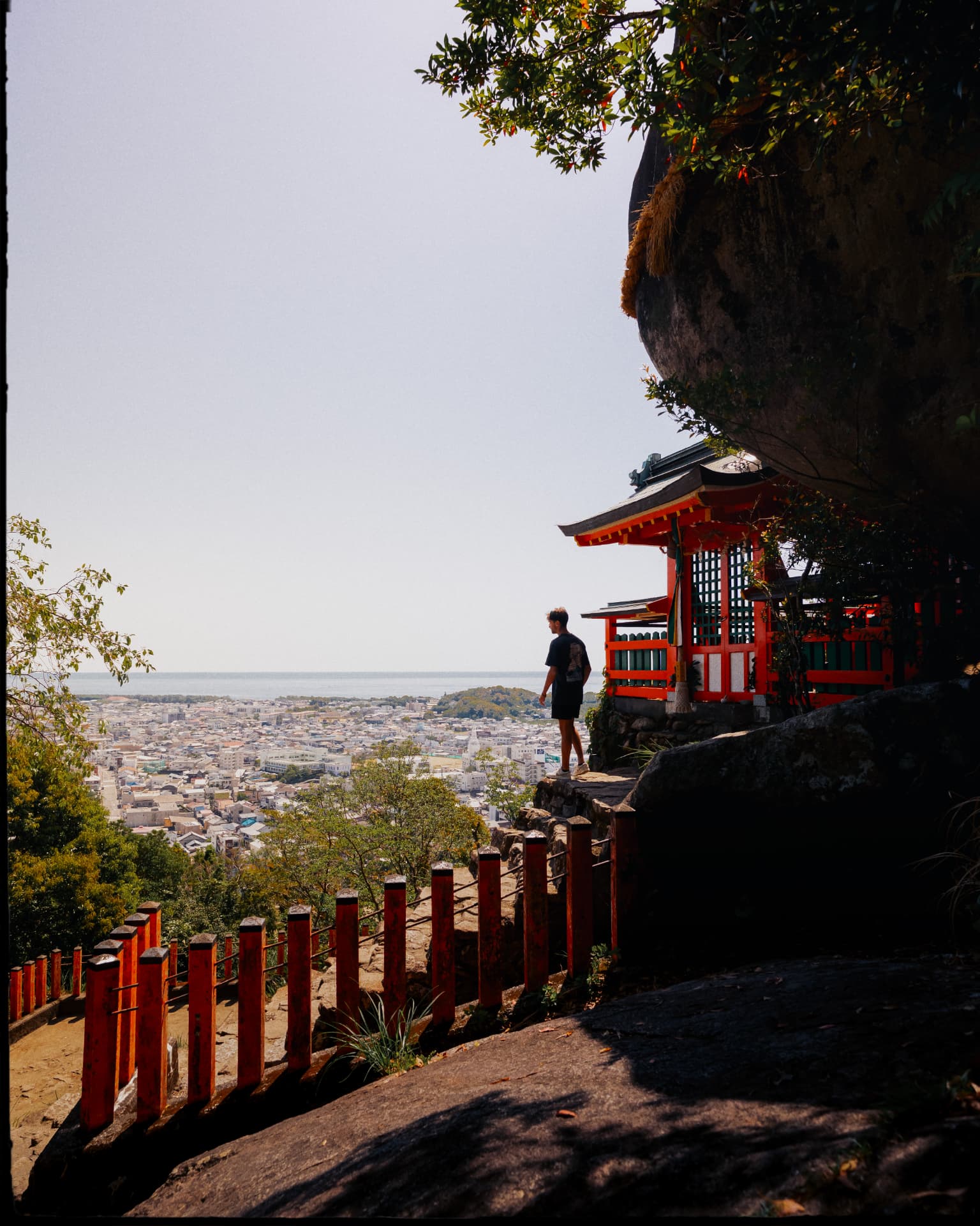 Sanctuaire rouge accroché à la falaise avec vue sur la ville et la mer